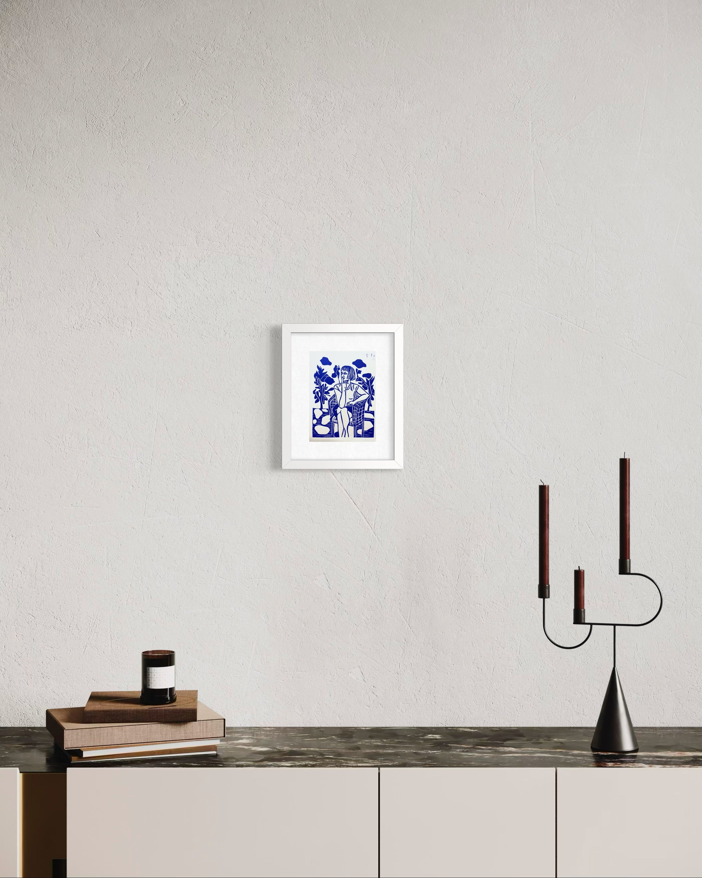 Framed artwork on a wall above a wooden surface with a modern candle holder.