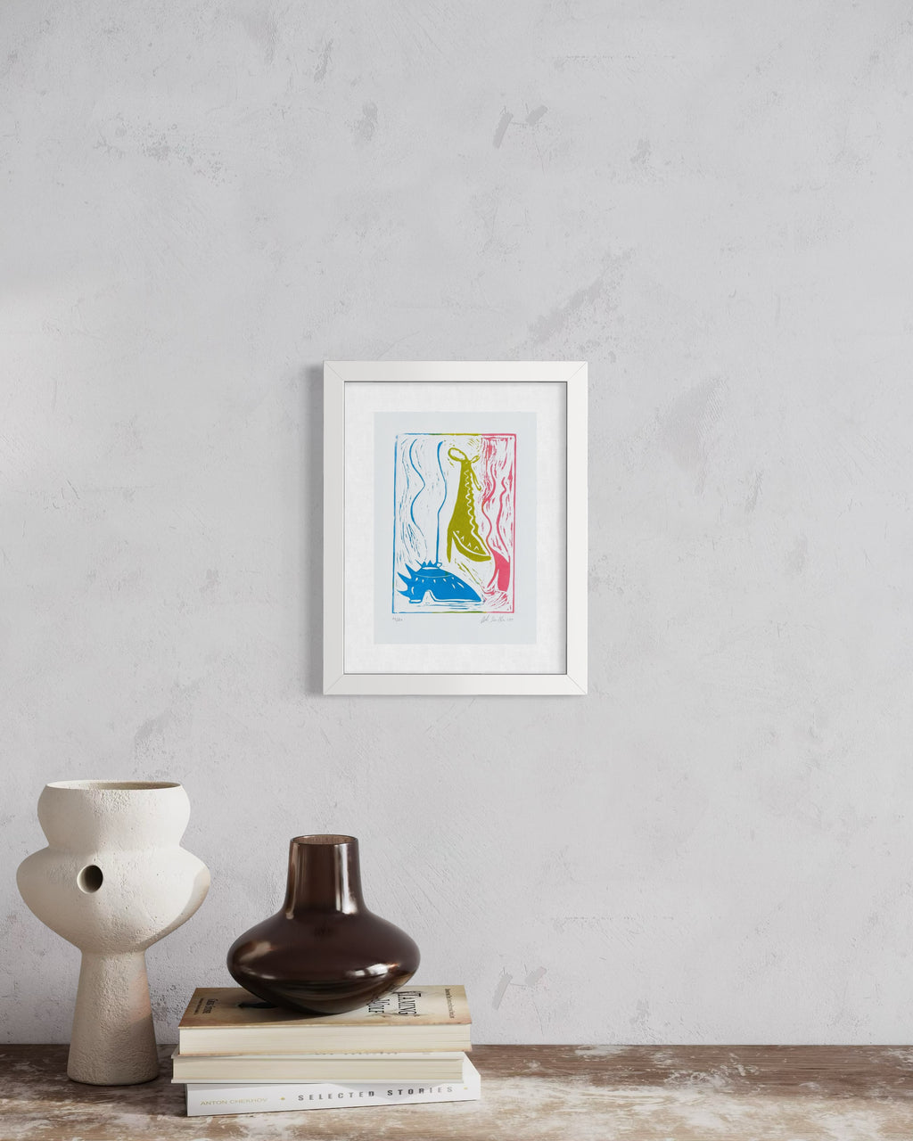 Framed artwork on a wall above books and vases