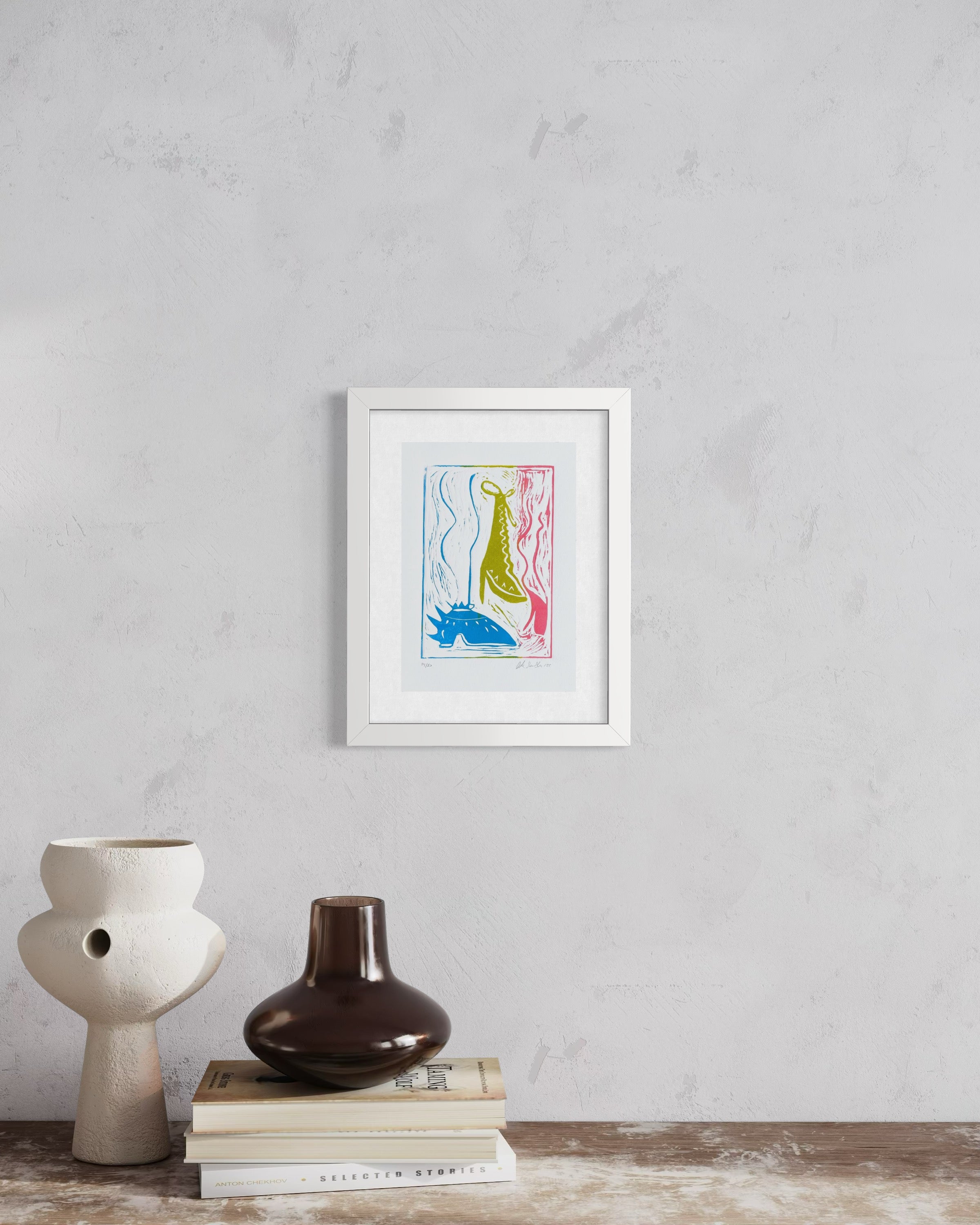 Framed artwork on a wall above books and vases