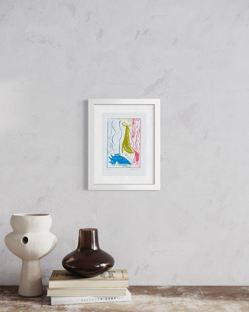 Framed artwork on a wall above books and vases