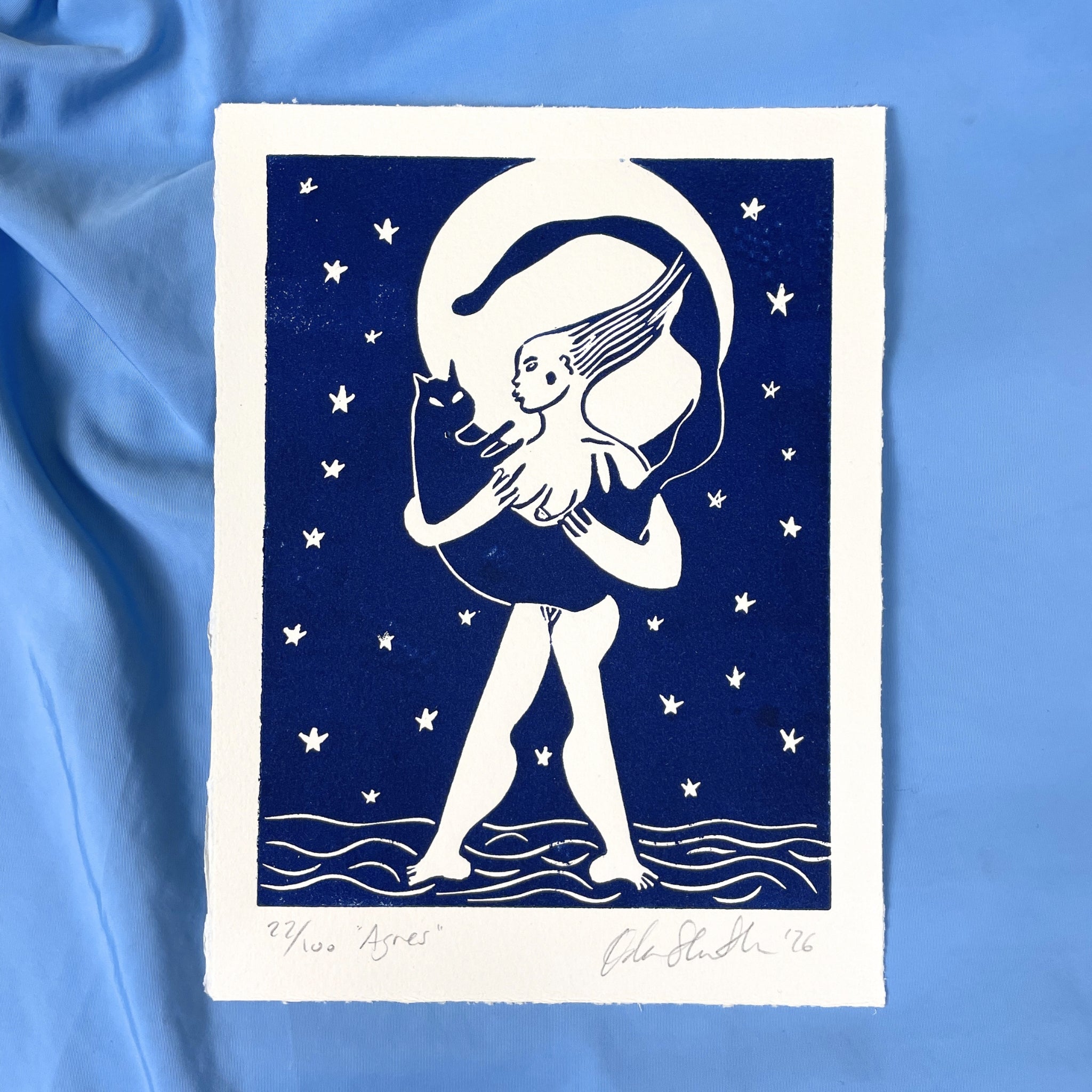 Art print of a stylized illustration of a person with a cat under a moonlit sky on a blue fabric background.