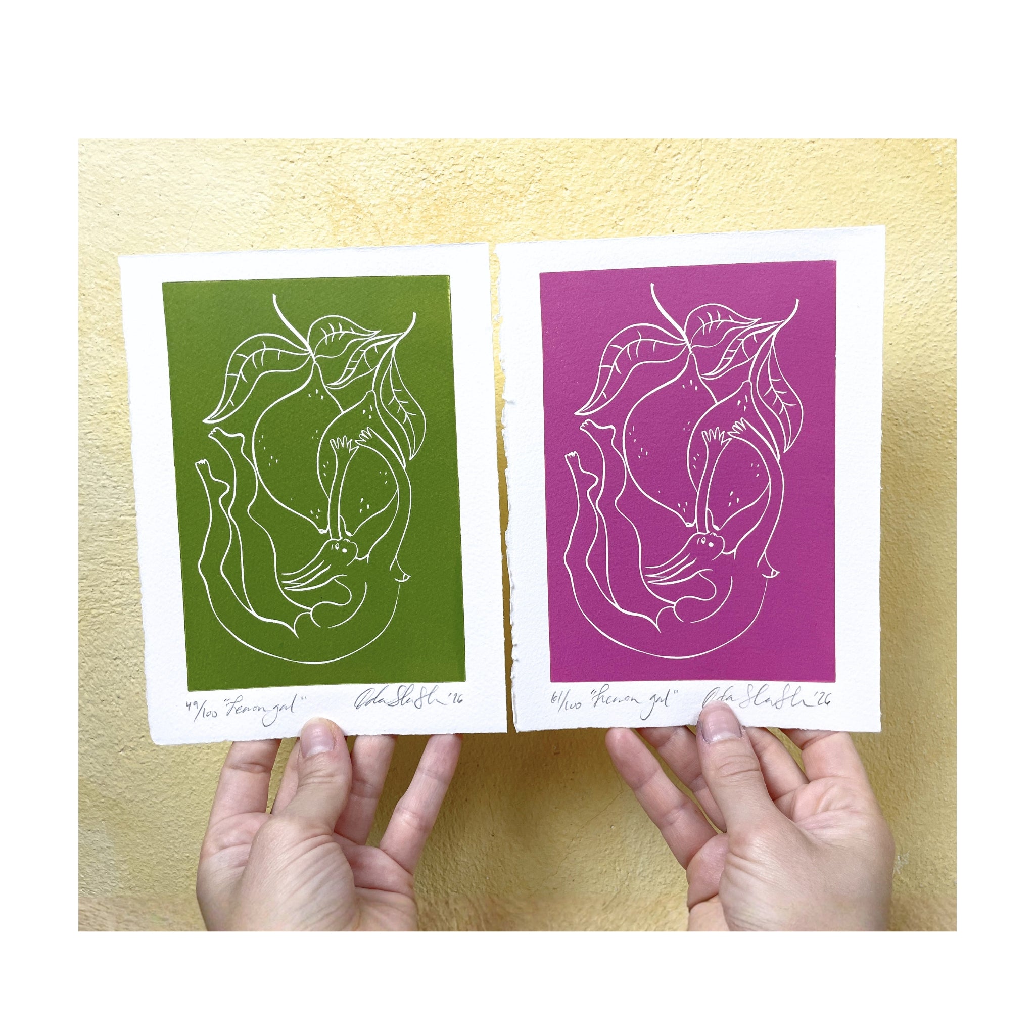 Two prints, one green and one pink, held by hands against a cream background.
