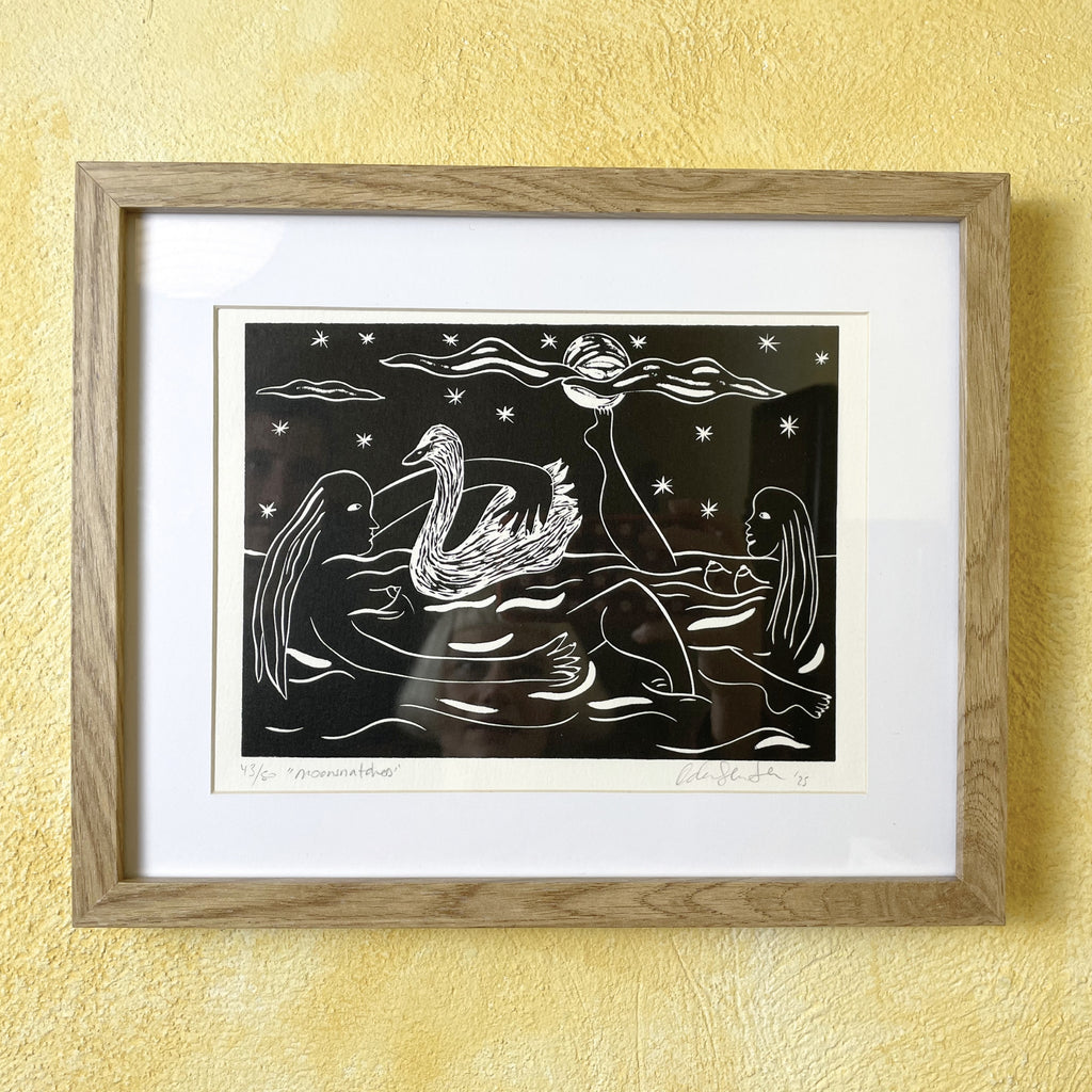 Framed artwork of a swan and woman on water with stars, against a yellow wall.