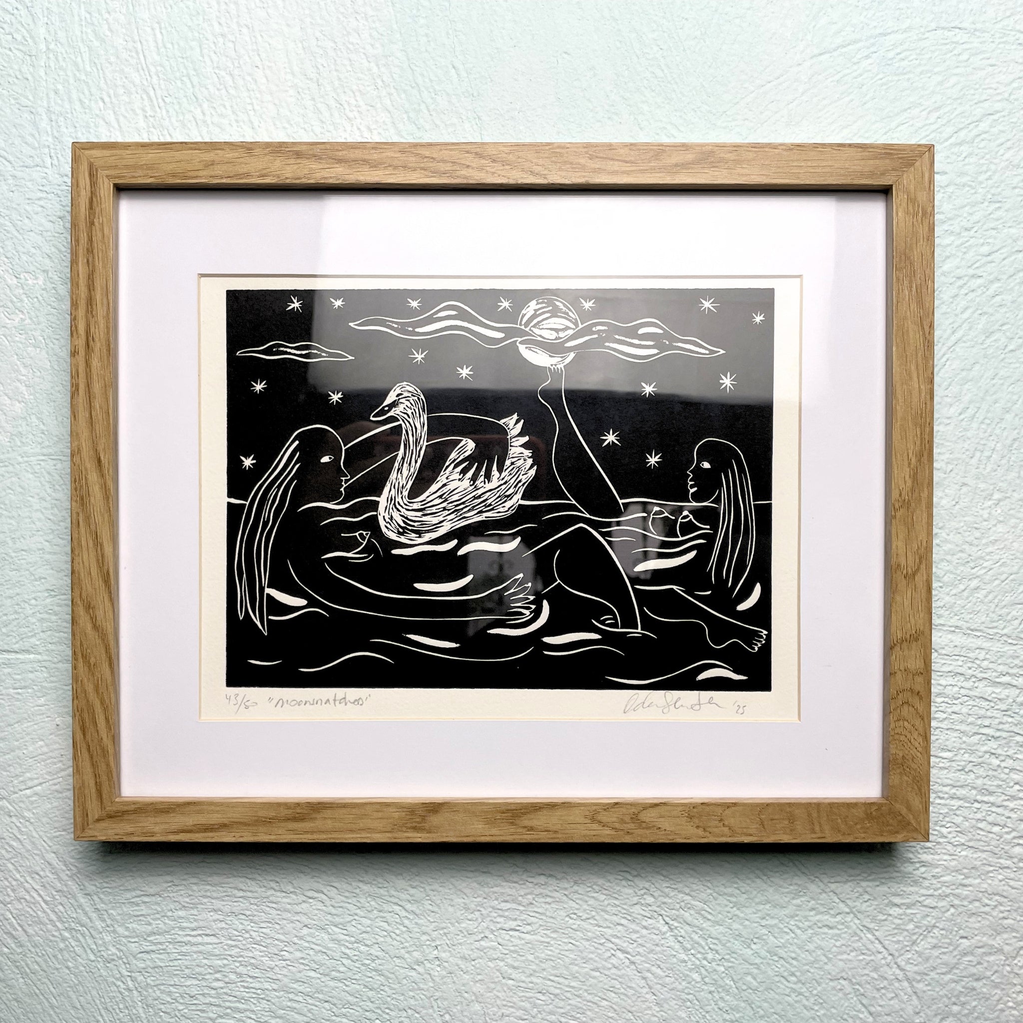 Framed artwork of a woman and a swan on water with a moonlit sky.