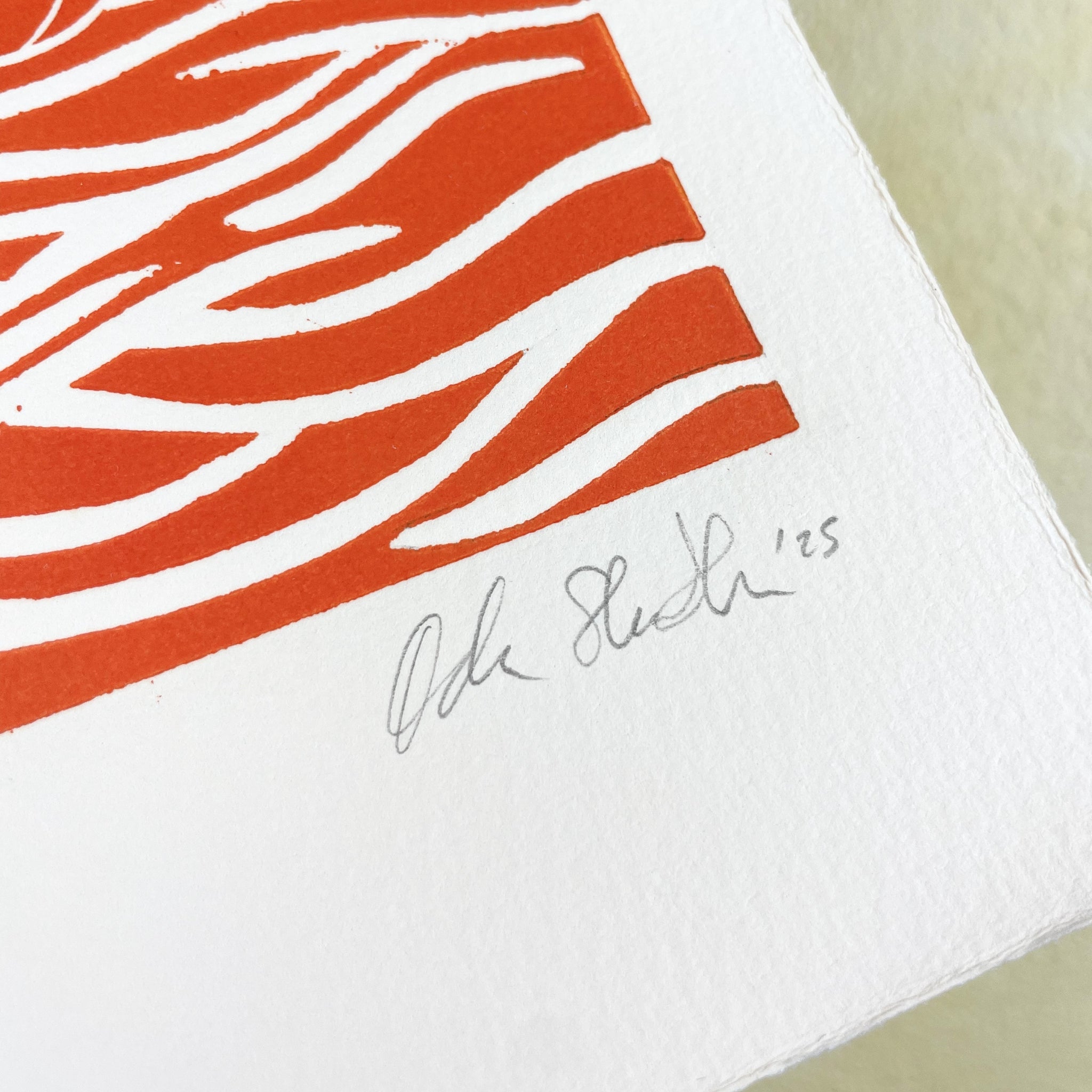 White paper with red abstract pattern and signature on a beige background