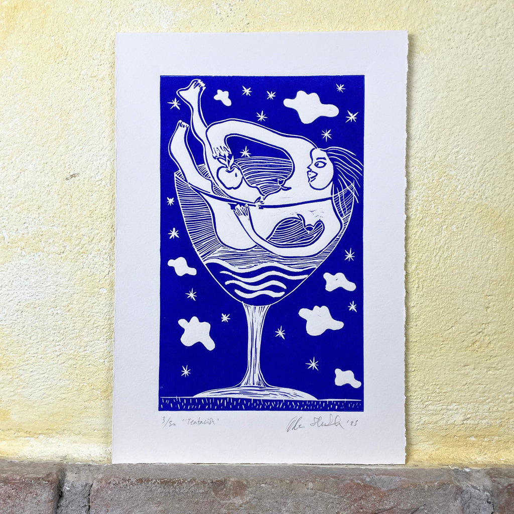 Art print of a woman in a wine glass with a blue background on a textured yellow wall.