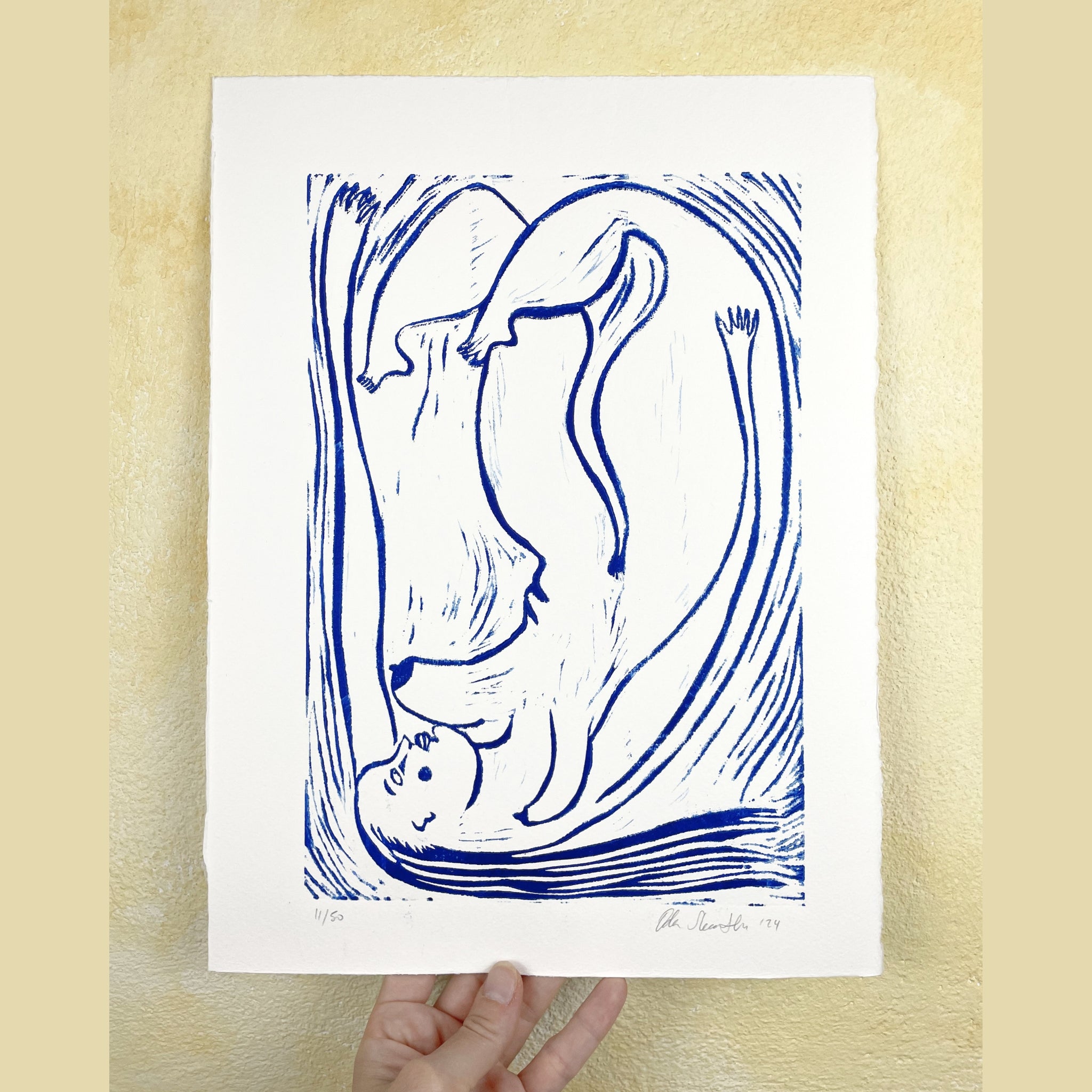 Blue and white abstract artwork held by a hand on a beige background