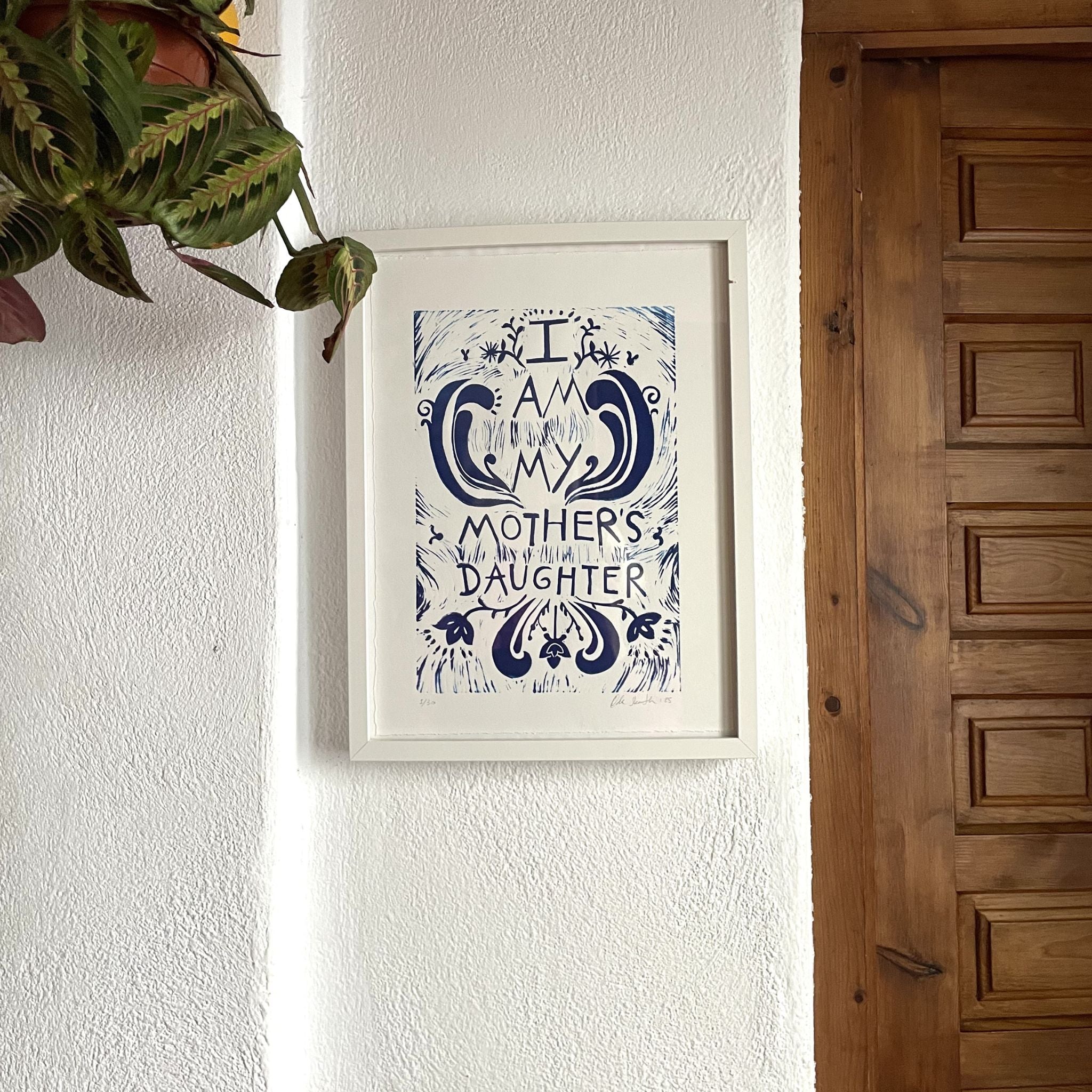 Framed artwork on a wall next to a wooden door