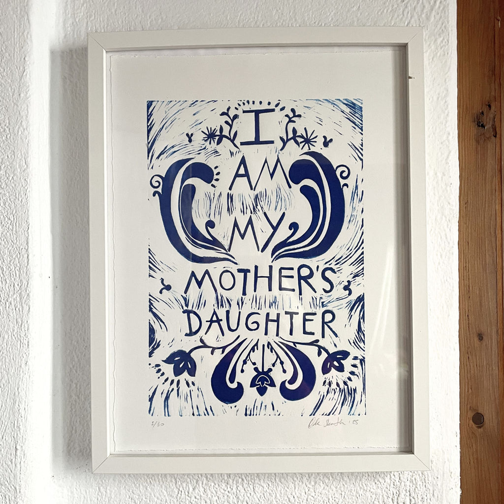 Framed artwork with 'I am my mother's daughter' text on a white wall.